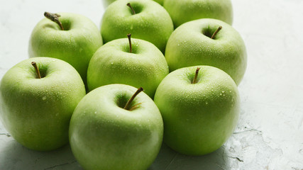Heap of solid fresh green apples covered with drops of water shining in daylight