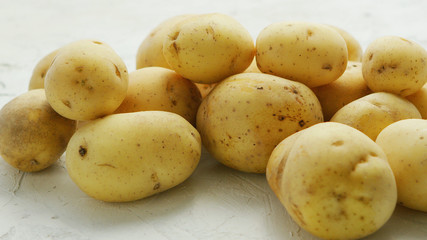 Closeup shot of pile of unpeeled clean potatoes composed on white surface in daylight 