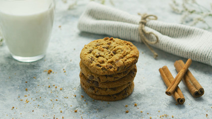 Composed stack of delicious chocolate chip cookies on table with cinnamon sticks and glass of milk