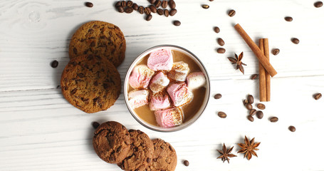 Top view of arranged white mug filled with cacao and sweet pink marshmallows on table with cookies and aromatic spices