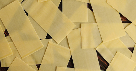 From above of chaotic arrangement of uncooked lasagna sheets lying on wooden table in mess
