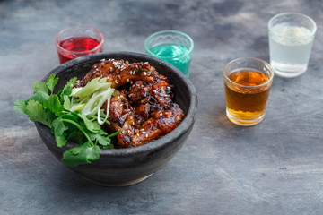 Spicy baked chicken wings in a bowl, dark background