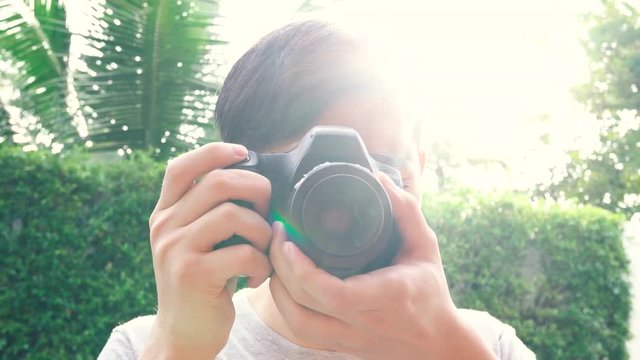 Young male photographer taking photos during sunset with back-lighting lens flare from behind