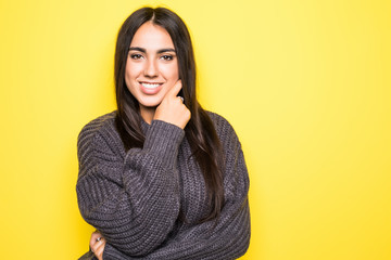 Cheerful beautiful young woman in sweater over yellow background