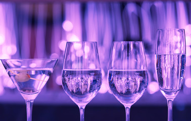 Row of Alcohol drinks against purple lights. 