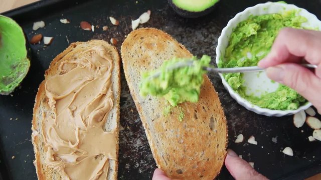 A woman puts avocado and slivered almonds on bread