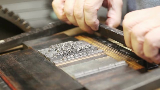 Printer secures a block of vintage type in a printing chase