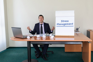 Young businessman sitting at his desk in the office taking a break from work to meditate with eyes closed, keep calm, no stress