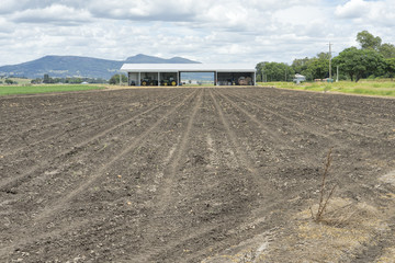 Freshly ploughed field with machinery shed in background