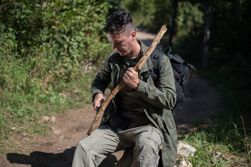 hiker making spear from old branch 