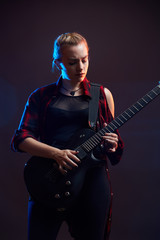 Blonde woman play guitar on stage, red, blue light dark scene