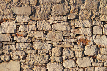 Ancient medieval stone masonry. Texture of a fragment of a wall of an old structure. A background for design and creative work. Decoration and exterior decoration of the building. Construction works.