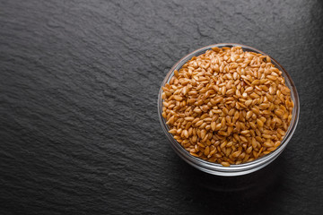 seeds of golden flax on a dark stone background