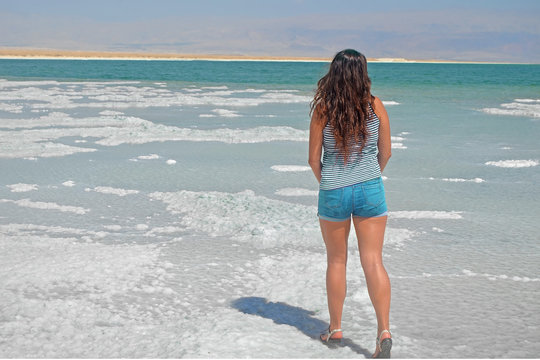 young girl looking into the distance to the mountains. brunette walks on the islands from salt in the dead sea, Israel