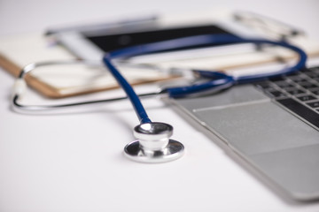 Workplace of doctor with laptop and stethoscope and notebook on white table top view shot.