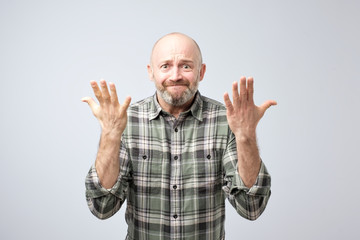 Naklejka premium Studio shot of excited over-emotive mature man pulling hands towards camera and arguing or showing regret