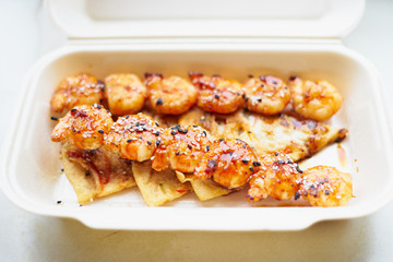 Grilled shrimps in sweet and sour sauce with different spices in a white box fast food top view