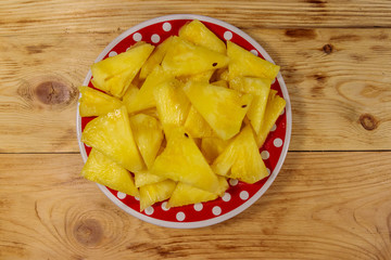 Pieces of pineapple in a plate on wooden table. Top view