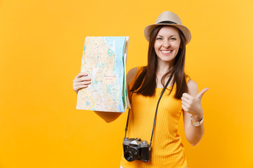 Traveler tourist woman in summer casual clothes, hat holding city map isolated on yellow orange background. Female passenger traveling abroad to travel on weekends getaway. Air flight journey concept.