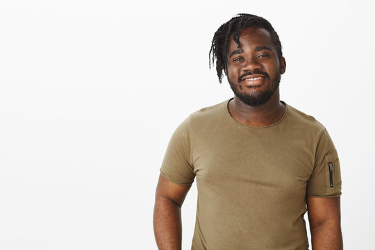 Waist-up Shot Of Charming Outgoing African American Guy With Beard And Moustache In Military T-shirt, Smiling Broadly And Standing Against Gray Background, Being Pleased While Talking To Girl