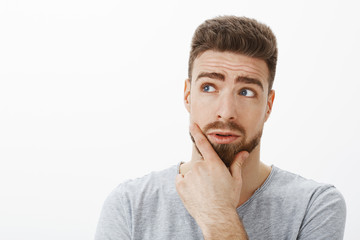 Curious and questioned handsome businessman trying solve problem thinking standing in thoughtful...