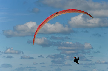 View from behind of a paraglider near Katwijk, Netherlands; alone in the blue sky with beautiful...
