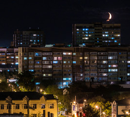 Fototapeta na wymiar City at night with new moon on dark sky
