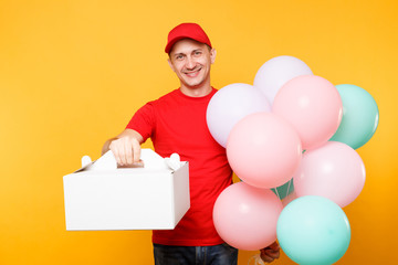 Man giving food order cake box isolated on yellow background. Male employee courier in red cap t-shirt hold colorful air balloons, dessert in empty cardboard box. Delivery service concept. Copy space.