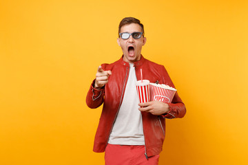 Portrait of vogue young man in 3d glasses, red leather jacket, t-shirt watching movie film, holding popcorn, cup of soda isolated on bright yellow background. People sincere emotions lifestyle concept
