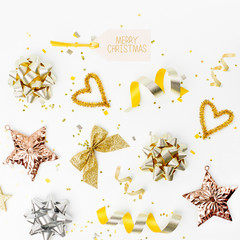 Christmas decorations, bows, stars,  bells in gold colors on white background with empty copy space for text. Holiday and celebration. Flat lay, top view