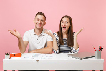 Two young smiling business woman man colleagues sit work at white desk with contemporary laptop...