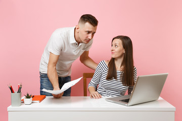 Two young angry business woman man colleagues sit work at white desk with contemporary laptop...