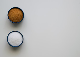 Ordinary and coconut sugar in plates on a white background. Тоp view. Copy space.