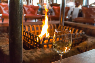 glass of white wine in front of a warm and comfortable fire place.