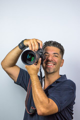 Gutgelaunter Fotograf mit SLR mit Zoomobjektiv in Studio