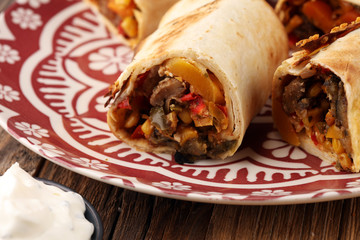 Burritos wraps with beef and vegetables on wooden background. Beef burrito, mexican food
