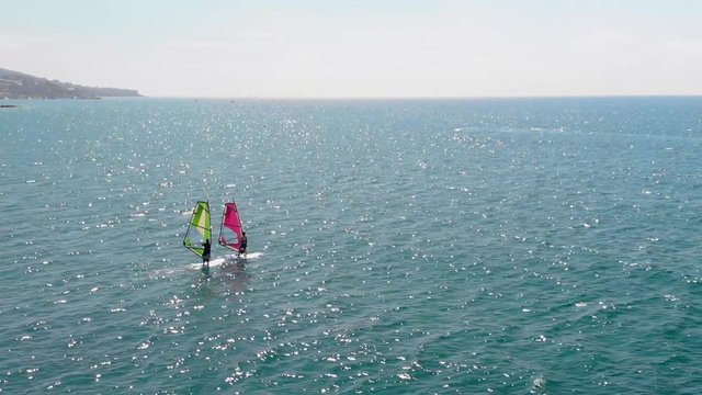 Cinematic aerial view of windsurfers sailing gliding across the sea extreme sport