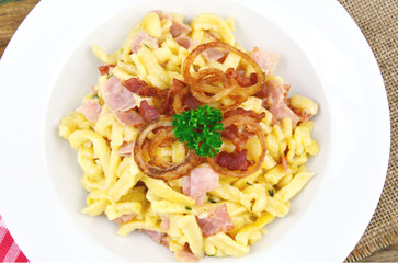 Spätzel or Spaetzel or soft egg noodle fried with ham ,cheese and Topped with fried onions and bacon.
