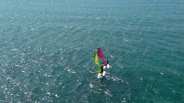 Cinematic aerial view of windsurfers sailing gliding across the sea extreme sport