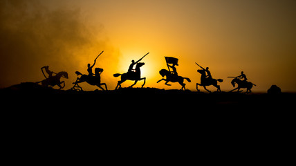 Attacking scene. War concept. Riders on horse ready to fight and soldiers on a dark foggy toned...