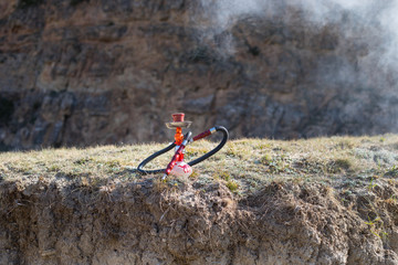Hookah, traditional arabic waterpipe, direct sunset light, outdoor photo. Mountain background or Silhouettes of hookah on sunset background. Outdoor. Selective focus