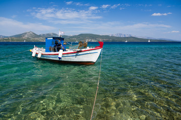 White fisher boat floats on crystal clear water in Greece