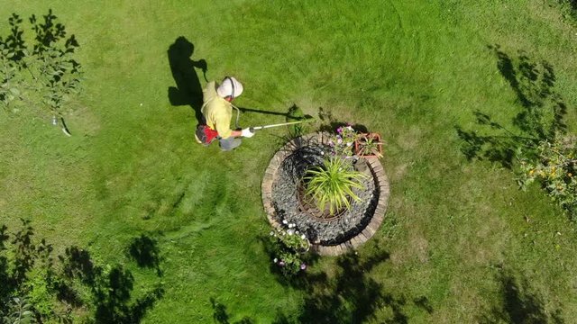 From height we, see gardener mows grass in garden