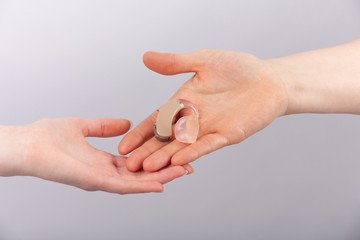Hands holding a hearing aid