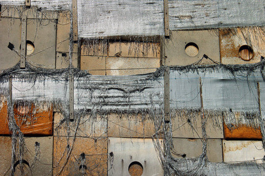 Old tattered wall insulation, torn nylon burlap sacks and wooden planks as background