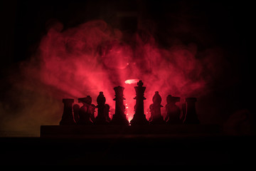 Man playing chess. Scary blurred silhouette of a person at the chessboard with chess figures. Dark toned foggy background.