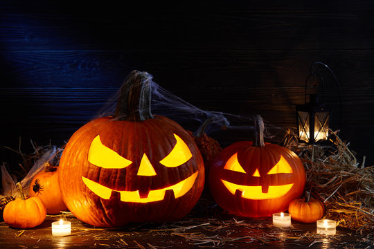 Carved pumpkins or jack-o-lanterns in dark barn, Halloween holiday celebration concept