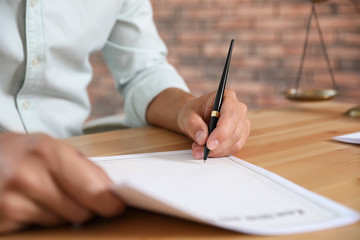 Male notary signing document at table in office, closeup