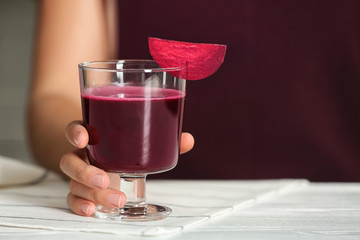 Woman with glass of beet smoothie at table, closeup