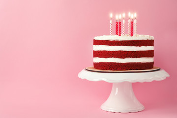 Delicious homemade red velvet cake with candles on pink background. Space for text